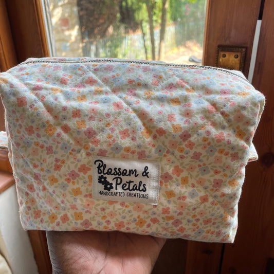 Floral fabric pouch held by a hand with 'Blossom & Petals' label.