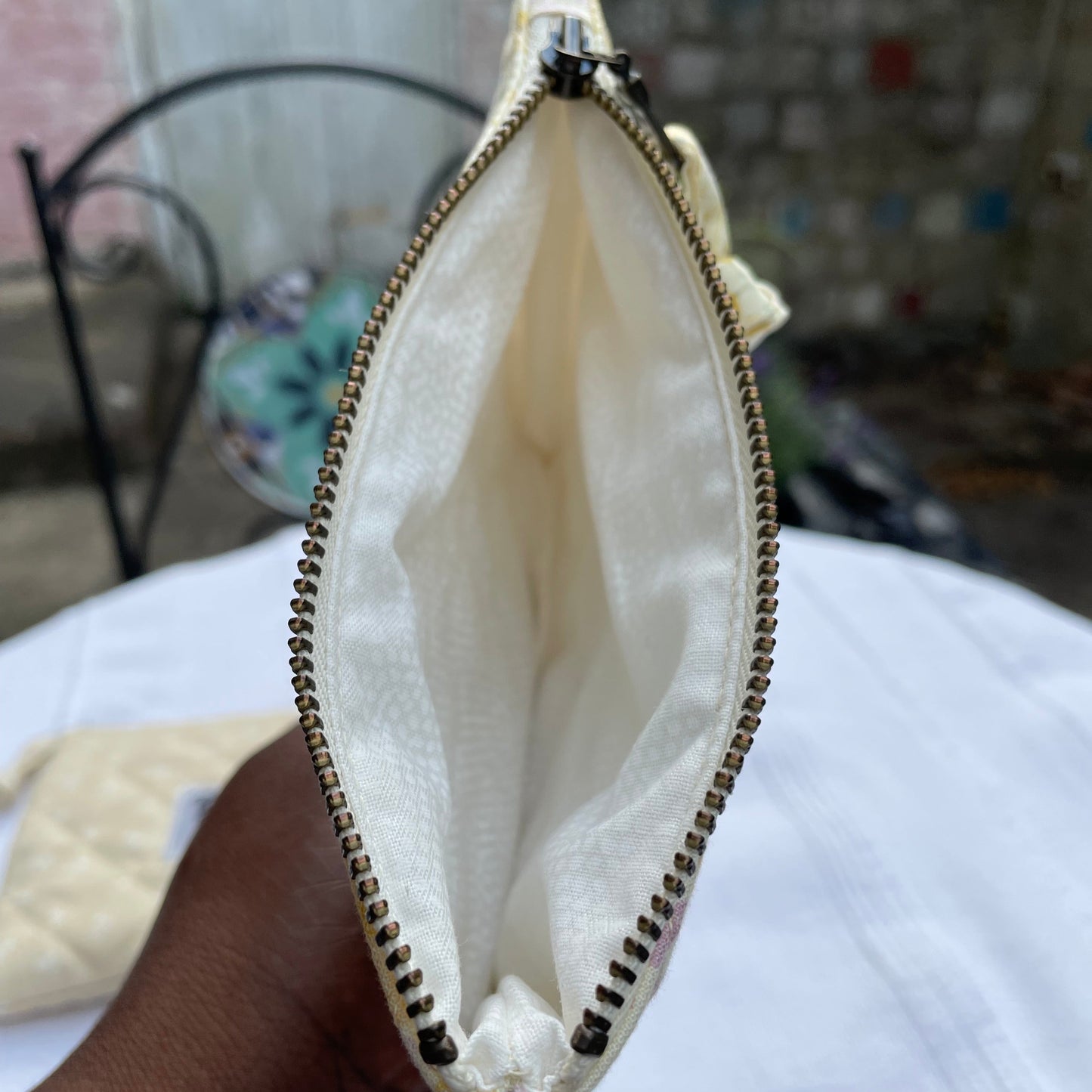 Cream Yellow floral pouch opened with white lining with a zipper, blurred background