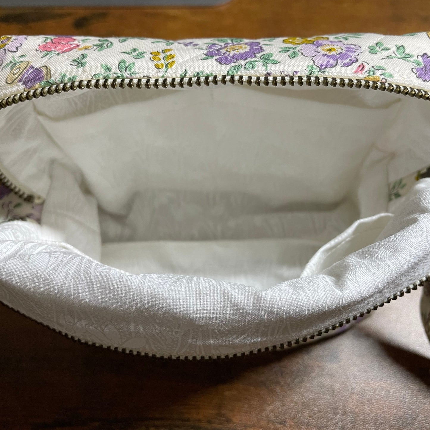 Floral-patterned fabric bag with a zipper on a wooden surface