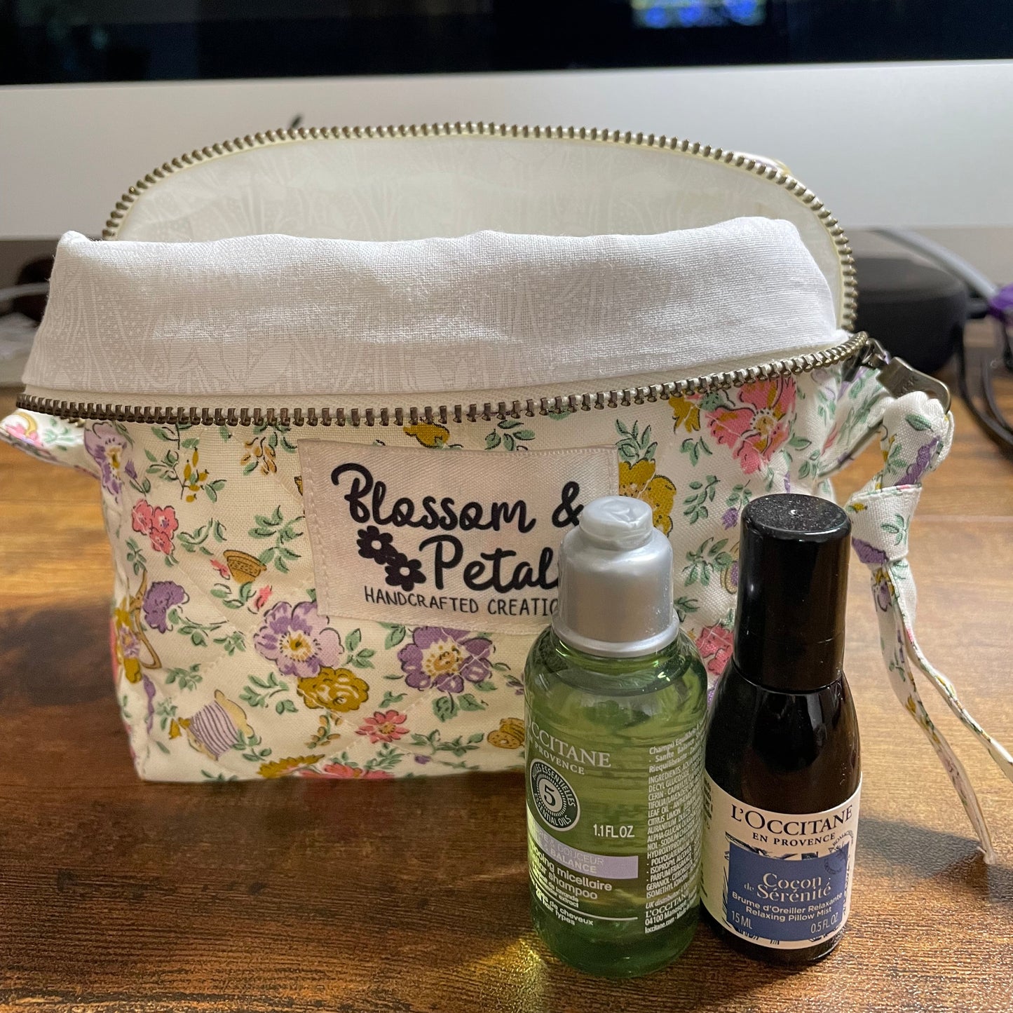 Floral-patterned pouch with two bottles on a wooden surface