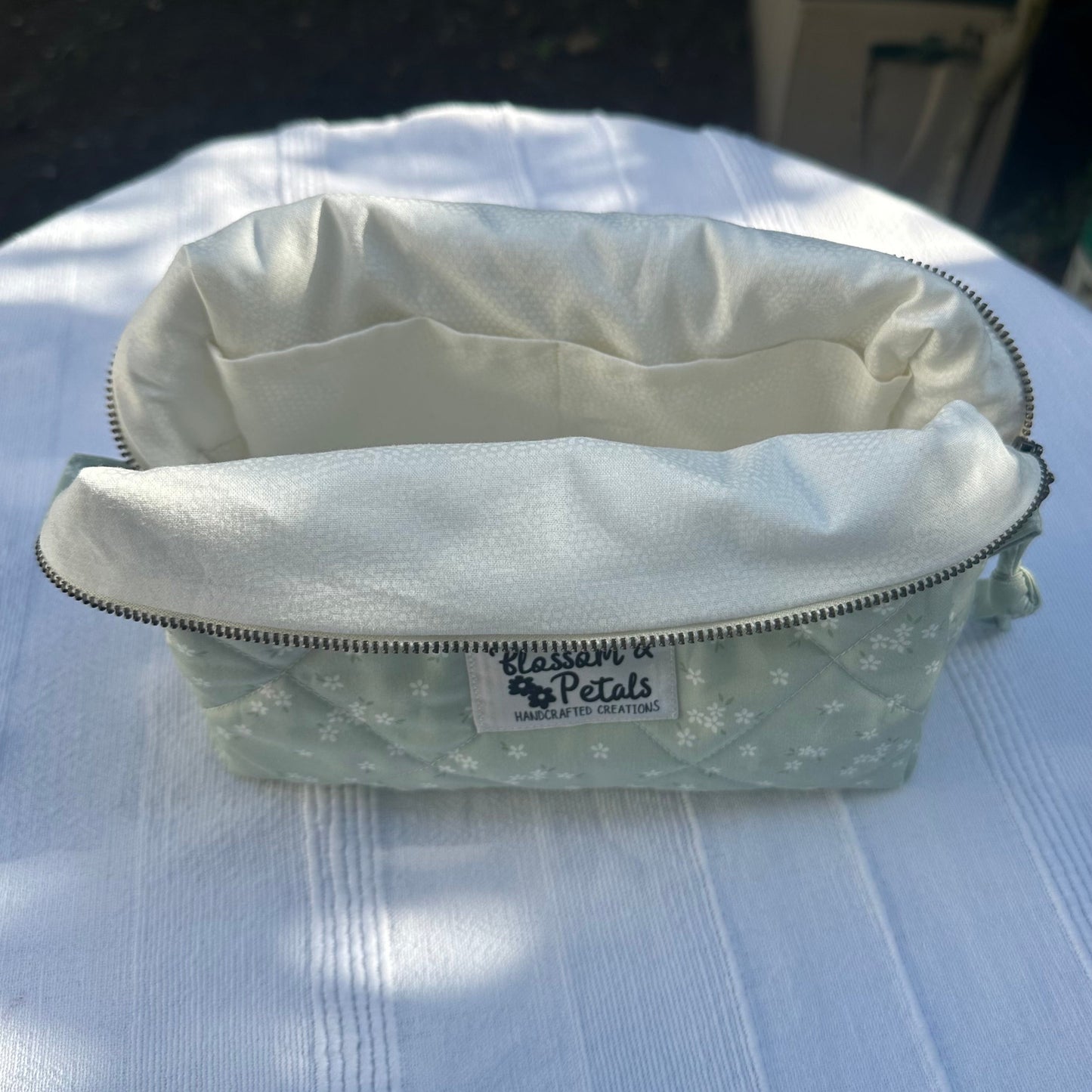 Light green pouch with floral pattern on a white surface