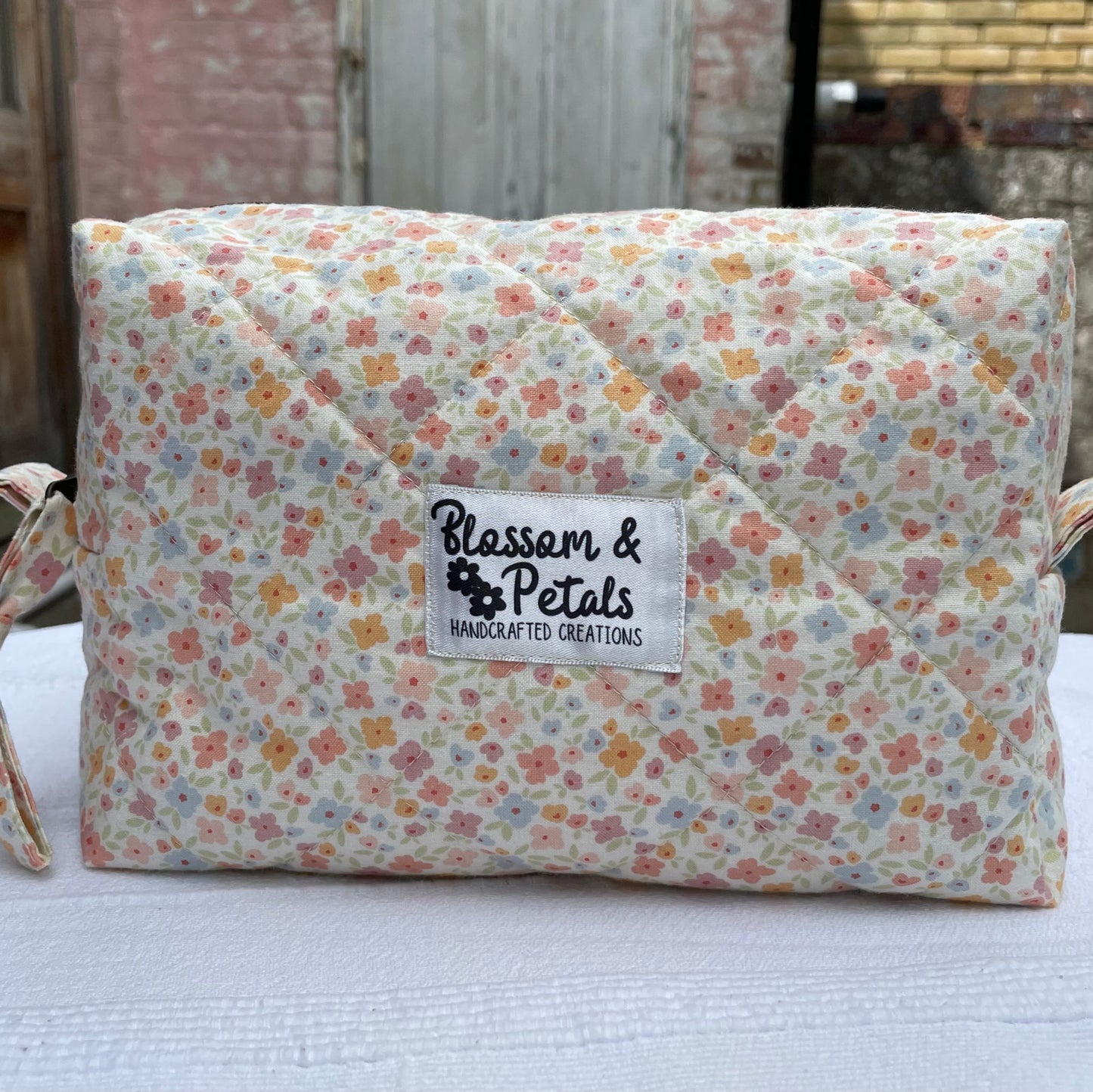 Handcrafted pastel floral quilted makeup bag by Blossom & Petals, featuring a delicate mini flower print and zipper closure, perfect for storing cosmetics, toiletries, or craft supplies