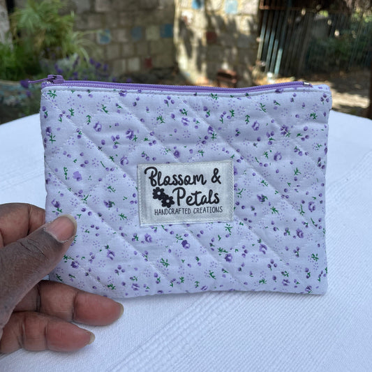 Purple and white quilted pouch with a visible brand label against a blurred background