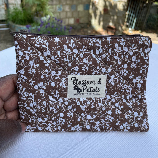 Brown Floral quilted patterned product with a visible brand logo held against a white background