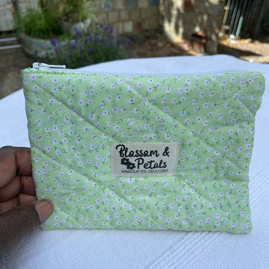 Green quilted pouch with floral pattern and 'Blossom & Petals' label held by a hand.