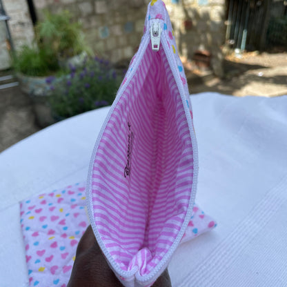 Close-up of a pink fabric pouch with colourful striped patterns on a white background.