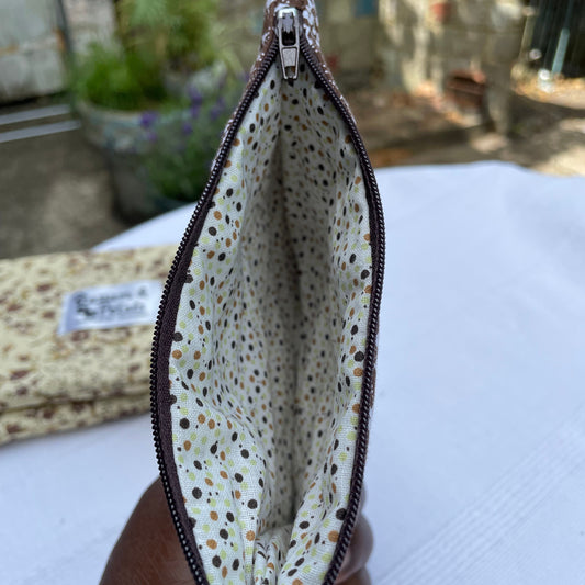 Small Brown quilted pouch with a polka dot interior held by a hand against a blurred background