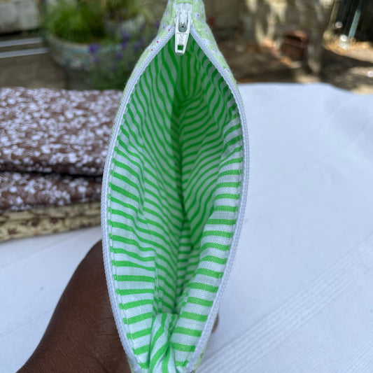 Green and white striped pouch held by a person with a blurred background