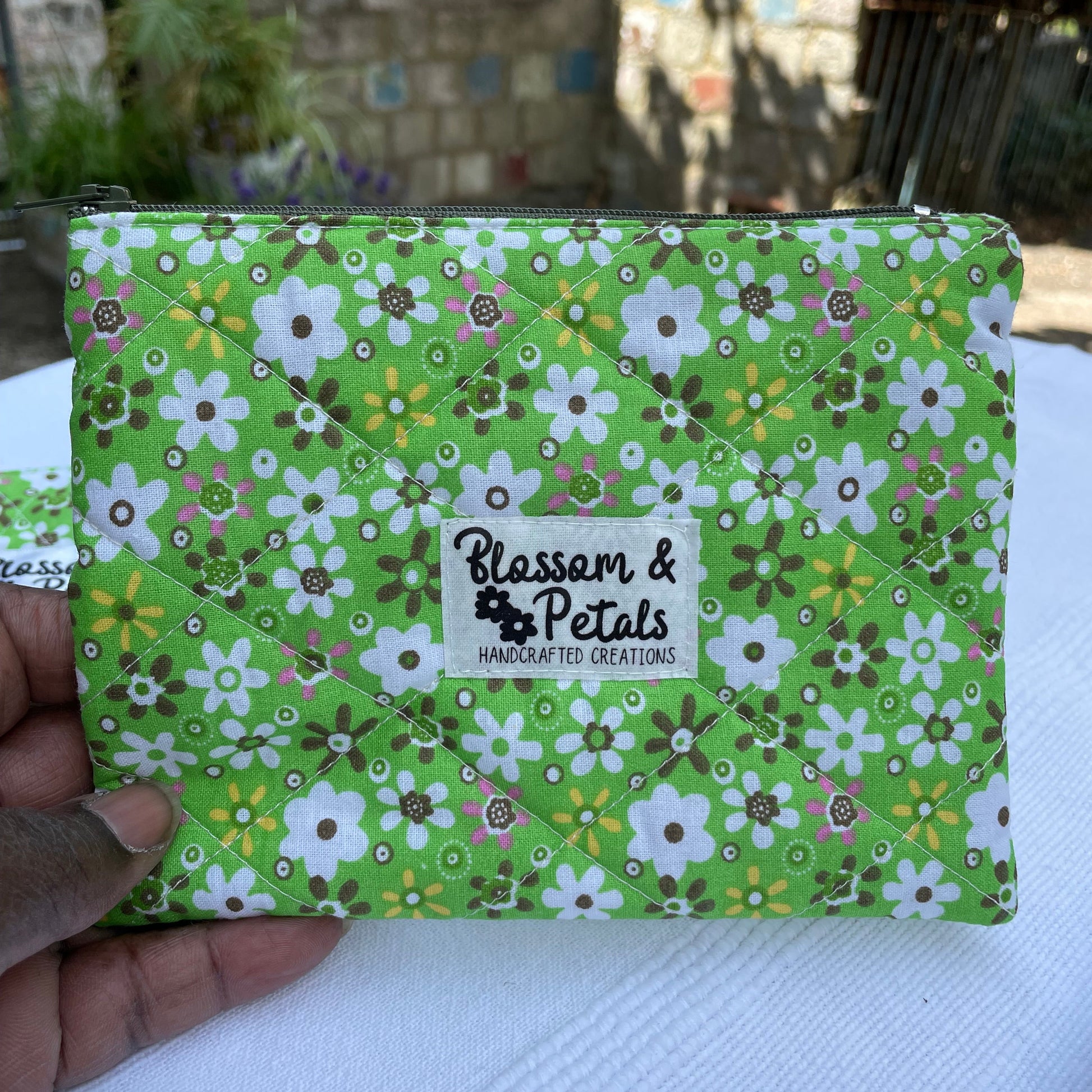 Green floral-patterned product with a visible brand logo held by a hand.
