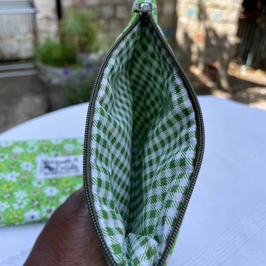 Green and white checkered pouch held by a hand with a blurred outdoor background