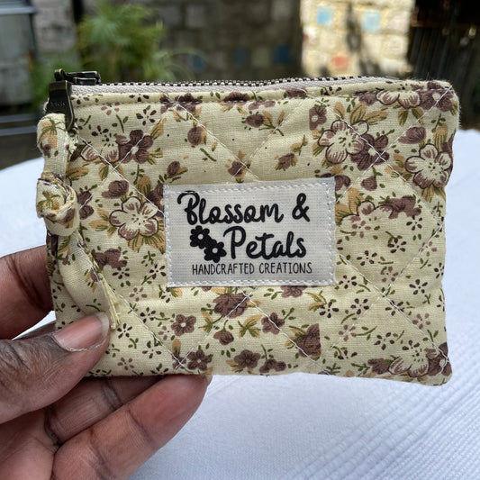 Floral patterned pouch held by a hand with a visible brand label.