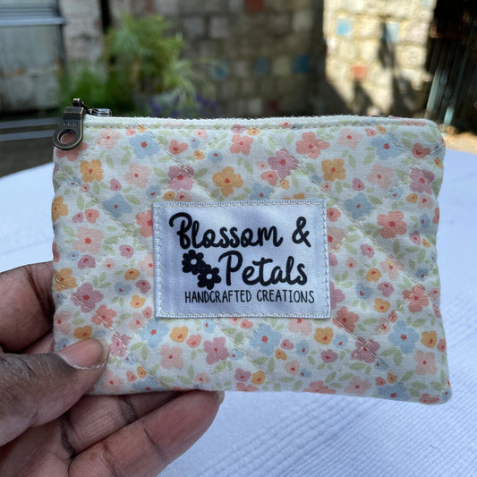 Floral fabric pouch held by a hand with 'Blossom & Petals' label.