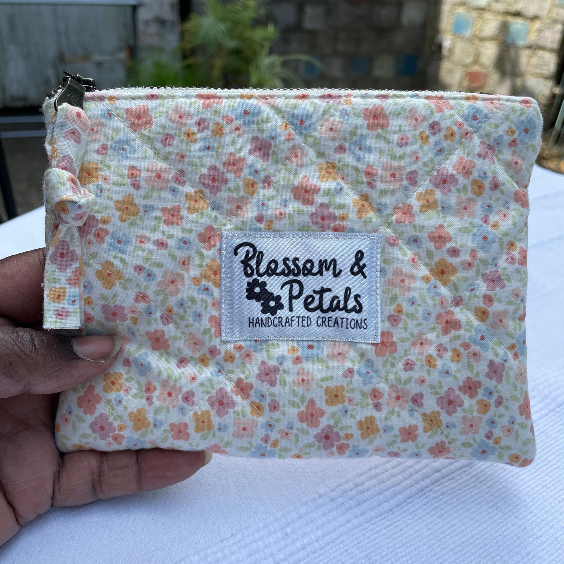 Floral-patterned product with a visible brand label held by a hand against a blurred background.