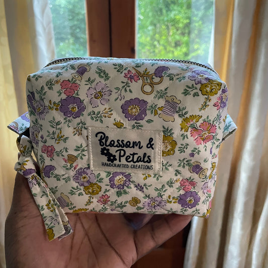 Floral-patterned pouch held by a hand with 'Blossom & Petals' branding.