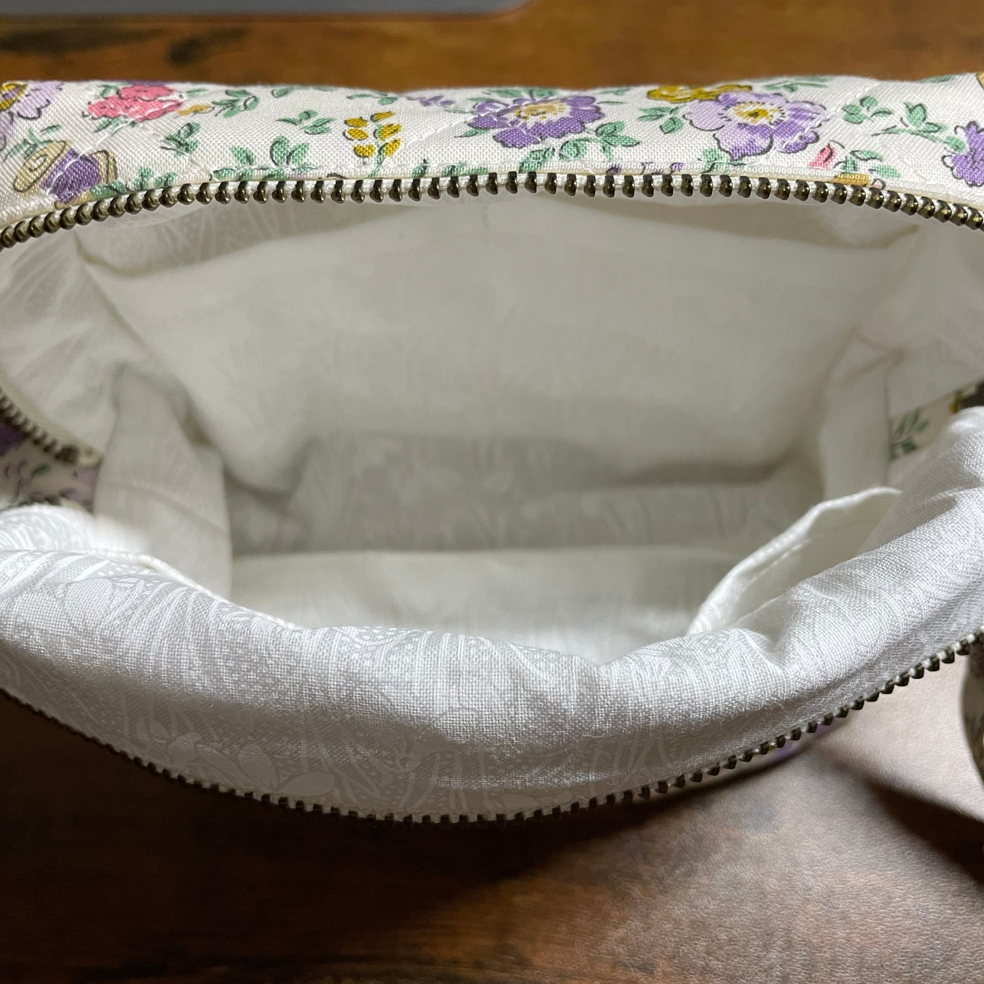 Floral-patterned fabric bag with a zipper on a wooden surface