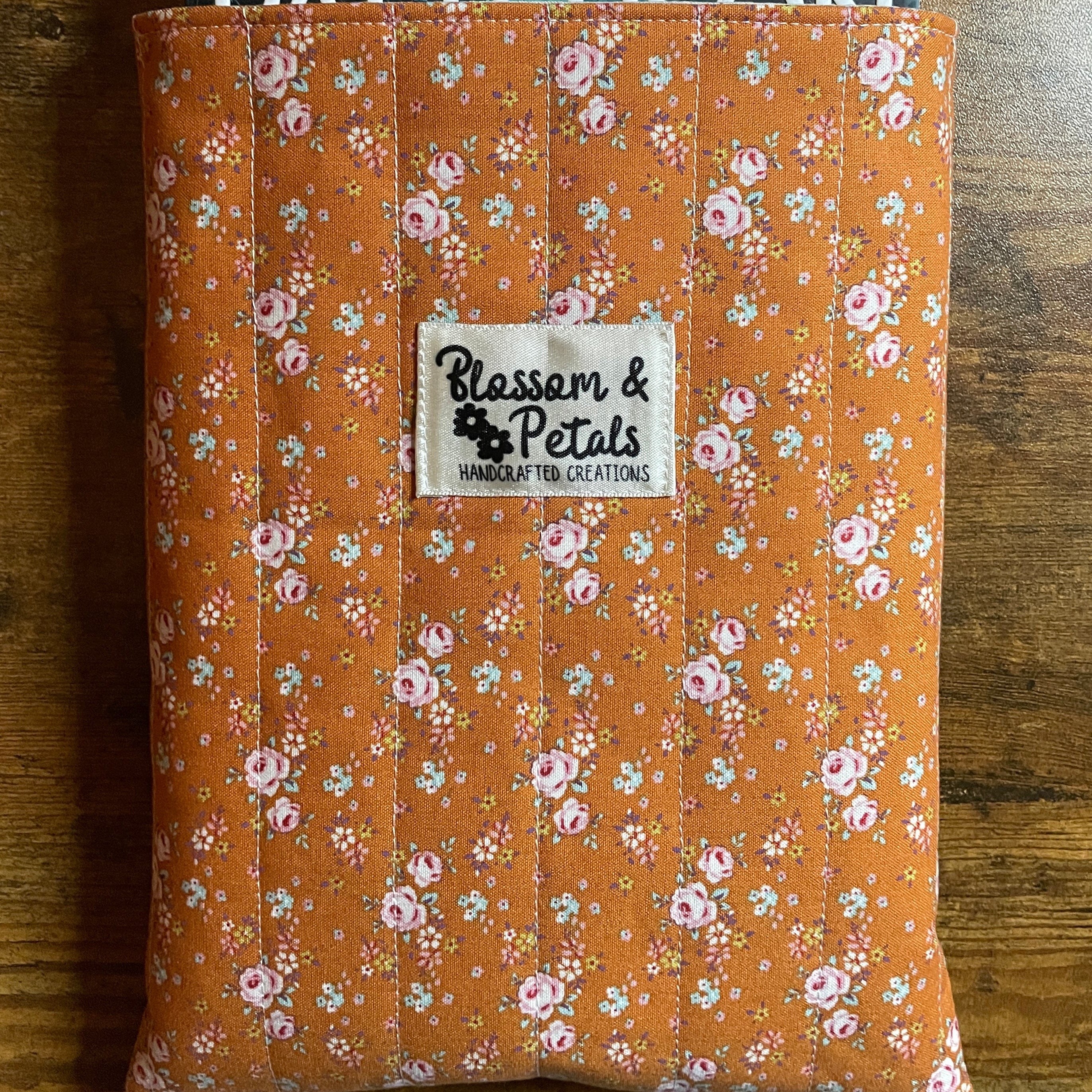Handmade quilted book sleeve in rust floral cotton fabric with padded design to protect books, journals, planners, and e-readers.