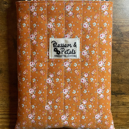 Handmade quilted book sleeve in rust floral cotton fabric with padded design to protect books, journals, planners, and e-readers.
