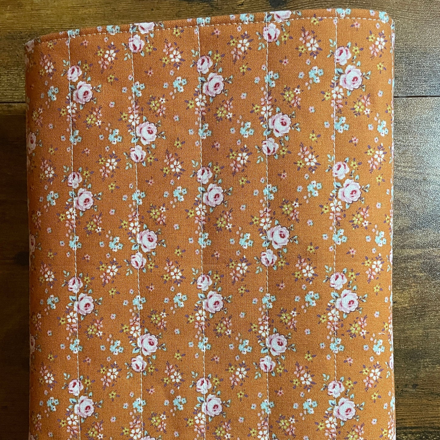 Handmade quilted book sleeve in rust floral cotton fabric with padded design to protect books, journals, planners, and e-readers.