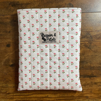 Handmade quilted white floral book sleeve with ditsy pink flower print and Blossom & Petals label, padded fabric book cover for books and journals.