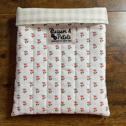 Handmade quilted white floral book sleeve with ditsy pink flower print and Blossom & Petals label, padded fabric book cover for books and journals.