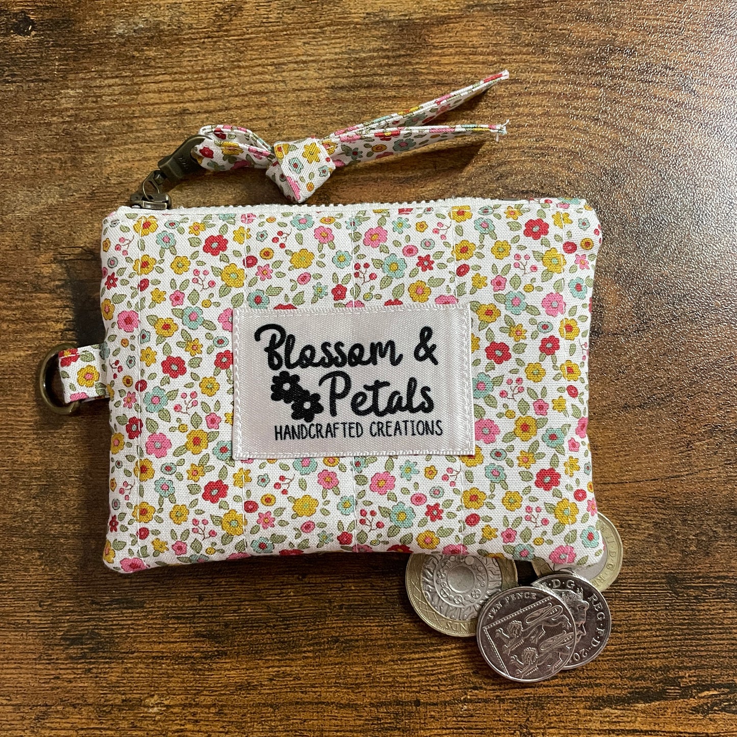 Handmade floral quilted zipper pouch in cotton fabric with branded label, ideal as a coin purse, small makeup bag, or everyday accessory pouch