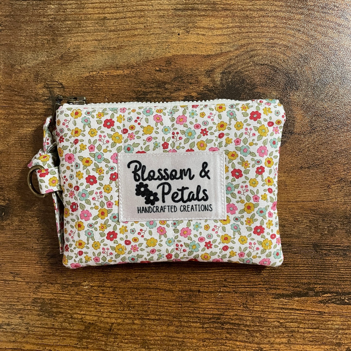 Handmade floral quilted zipper pouch in cotton fabric with branded label, ideal as a coin purse, small makeup bag, or everyday accessory pouch