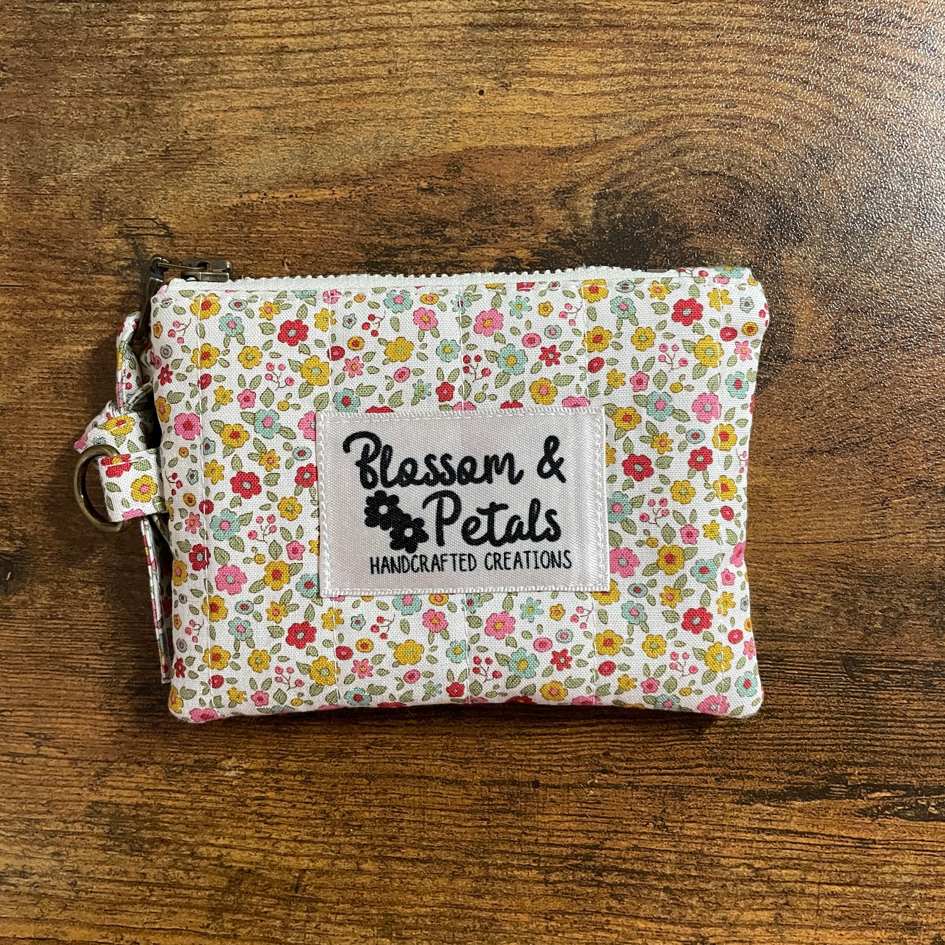 Handmade floral quilted zipper pouch in cotton fabric with branded label, ideal as a coin purse, small makeup bag, or everyday accessory pouch