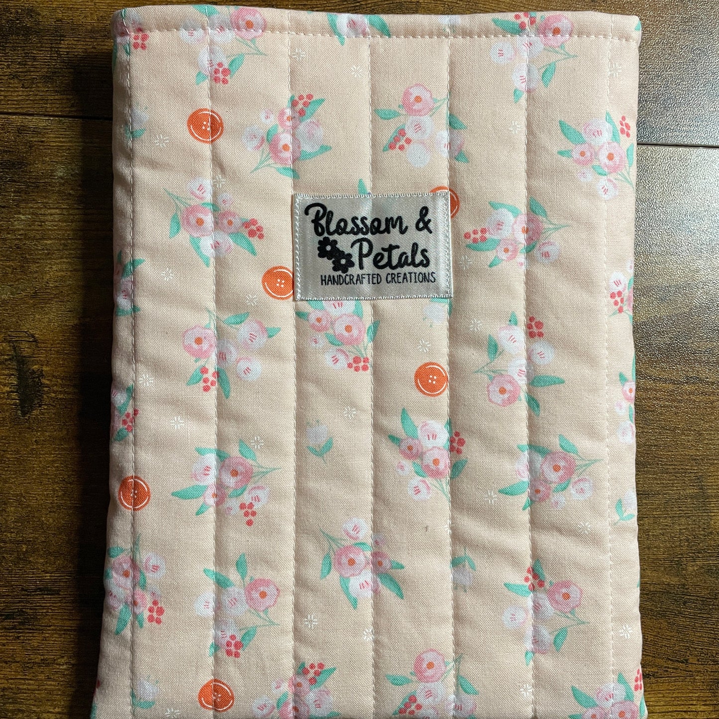 Handmade quilted peach floral book sleeve with soft cotton fabric and Blossom & Petals label, padded book cover for books, journals, and planners.