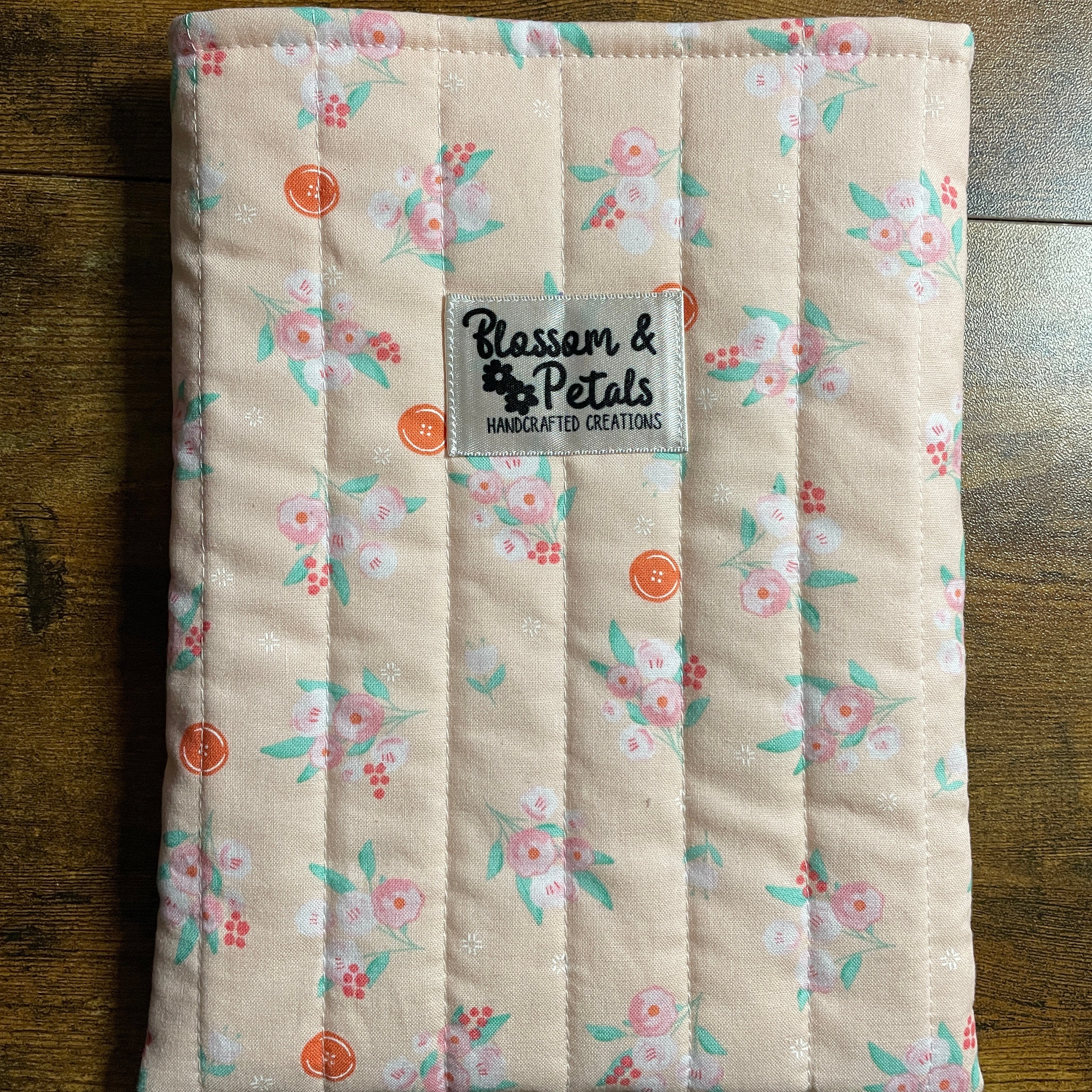 Handmade quilted peach floral book sleeve with soft cotton fabric and Blossom & Petals label, padded book cover for books, journals, and planners.