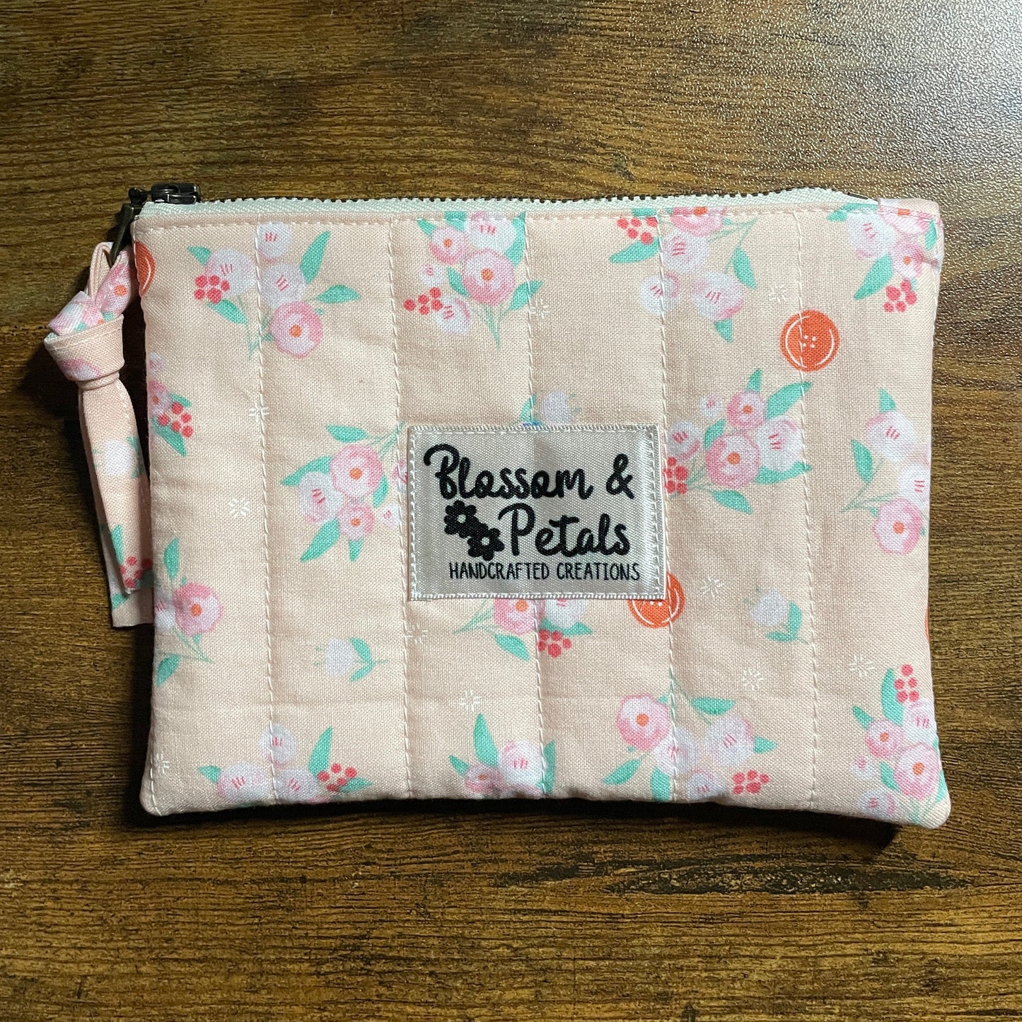 Handmade pastel floral quilted zipper pouch in peach fabric with zipper closure and Blossom & Petals label.