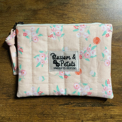 Handmade pastel floral quilted zipper pouch in peach fabric with zipper closure and Blossom & Petals label.