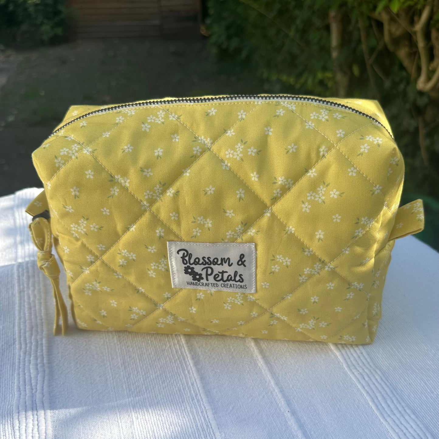 Handmade yellow quilted medium makeup bag with small white floral print, zipper closure, perfect for cosmetics and toiletries.