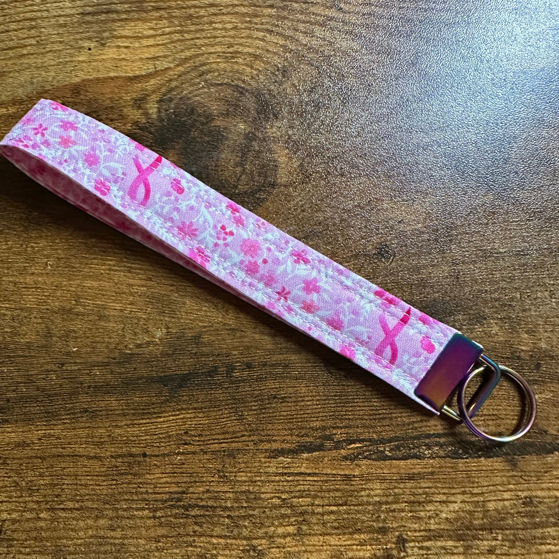 Keychain with pink ribbon pattern on a wooden surface