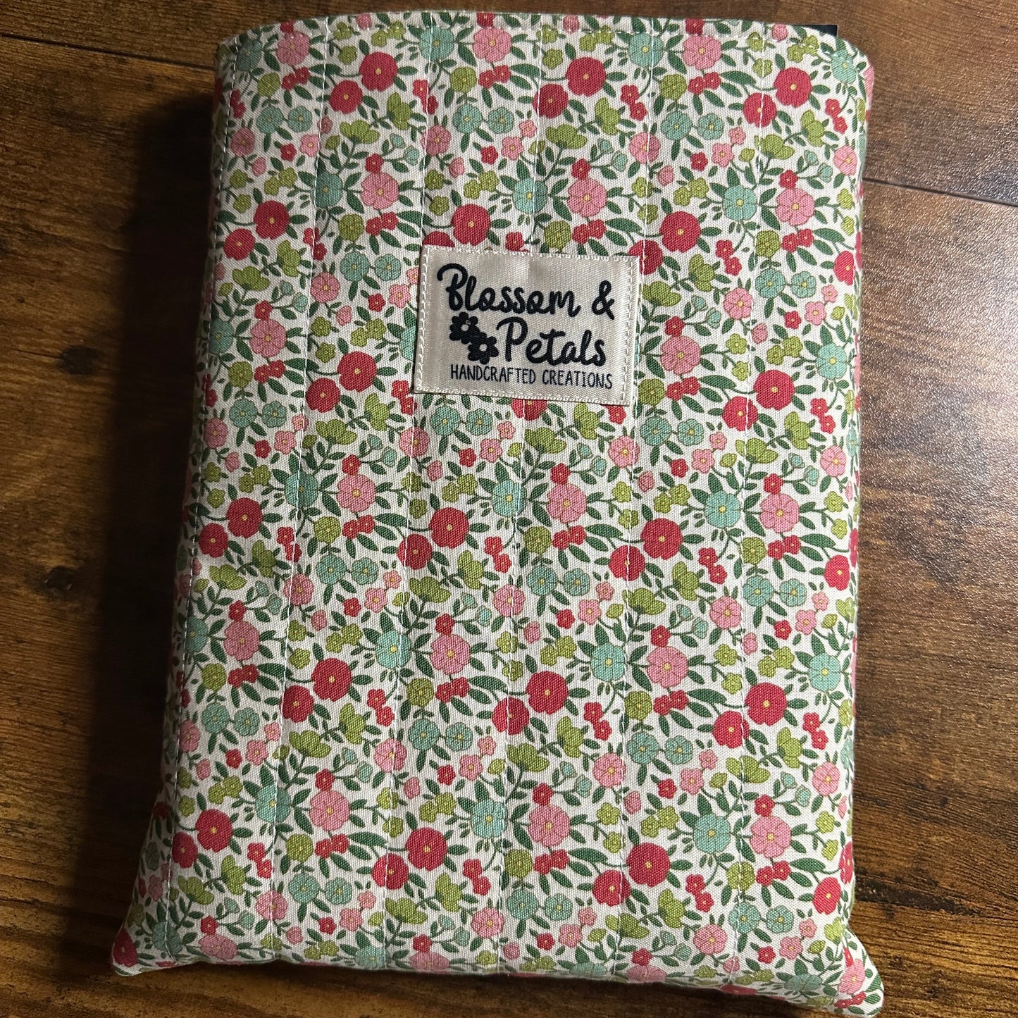 Handmade quilted floral book sleeve with padded cotton fabric for protecting books, journals, planners, and e-readers.