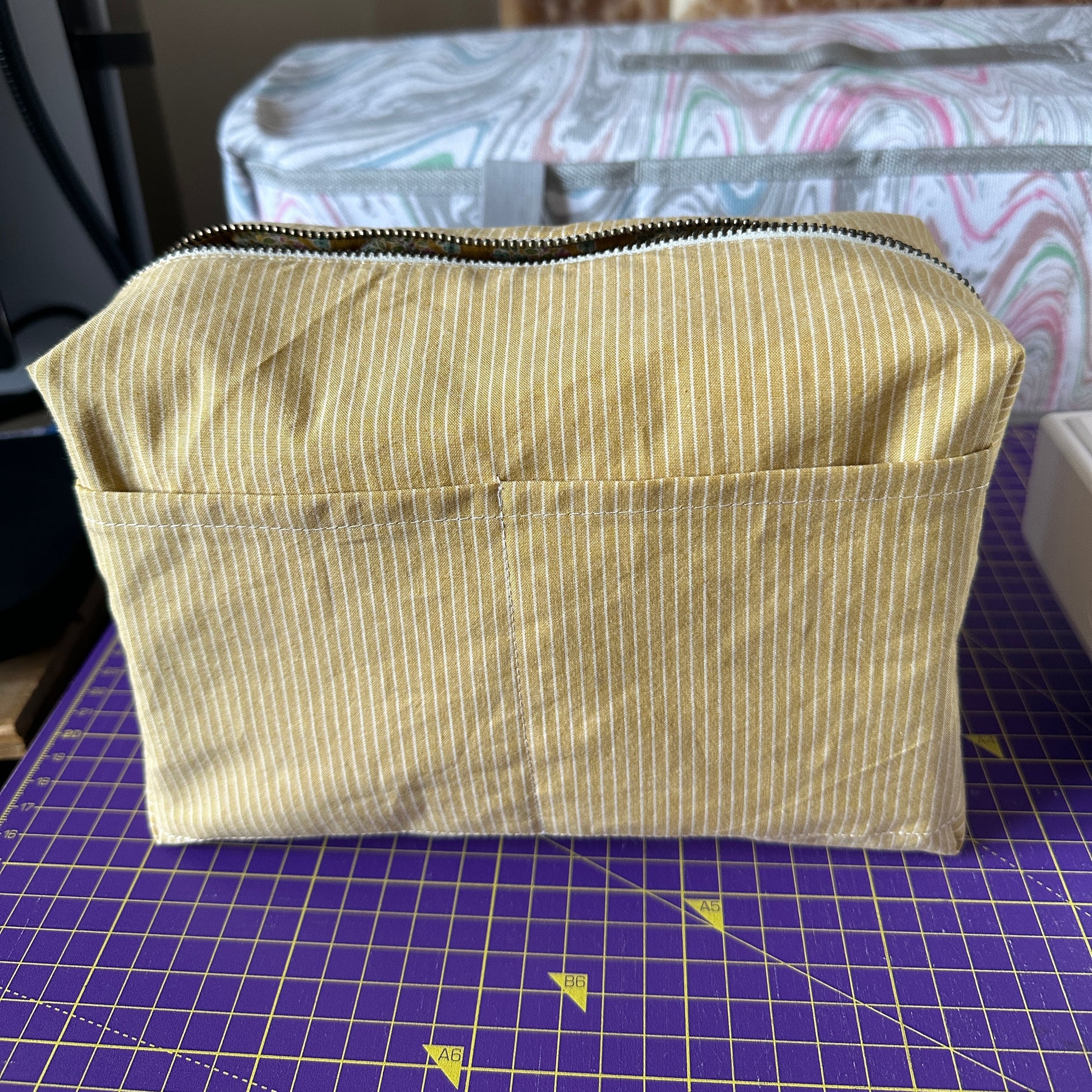 Handmade mustard yellow quilted makeup bag turned inside out to show interior material fabric which is yellow stripes