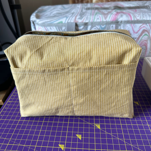 Handmade mustard yellow quilted makeup bag turned inside out to show interior material fabric which is yellow stripes