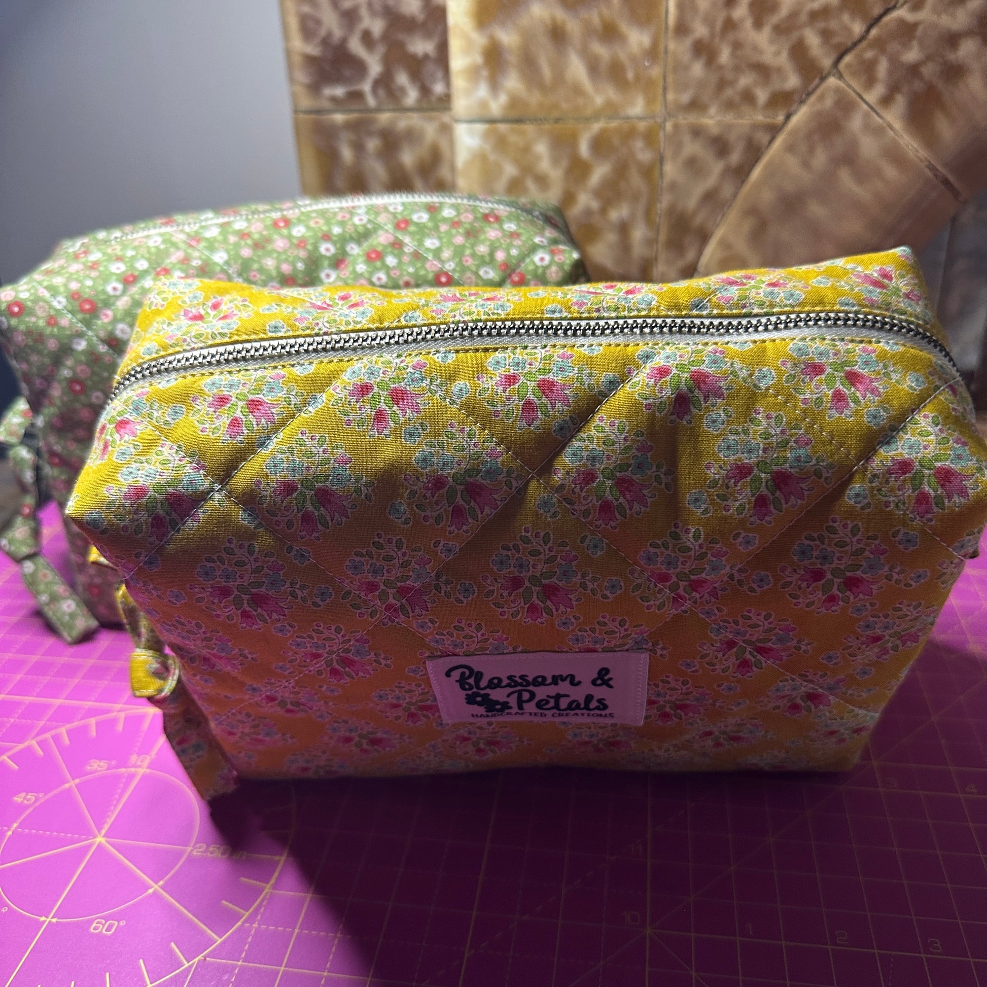 Handmade mustard yellow quilted makeup bag with floral cotton print, zippered cosmetic pouch for makeup, toiletries, and travel storage.