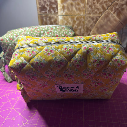 Handmade mustard yellow quilted makeup bag with floral cotton print, zippered cosmetic pouch for makeup, toiletries, and travel storage.