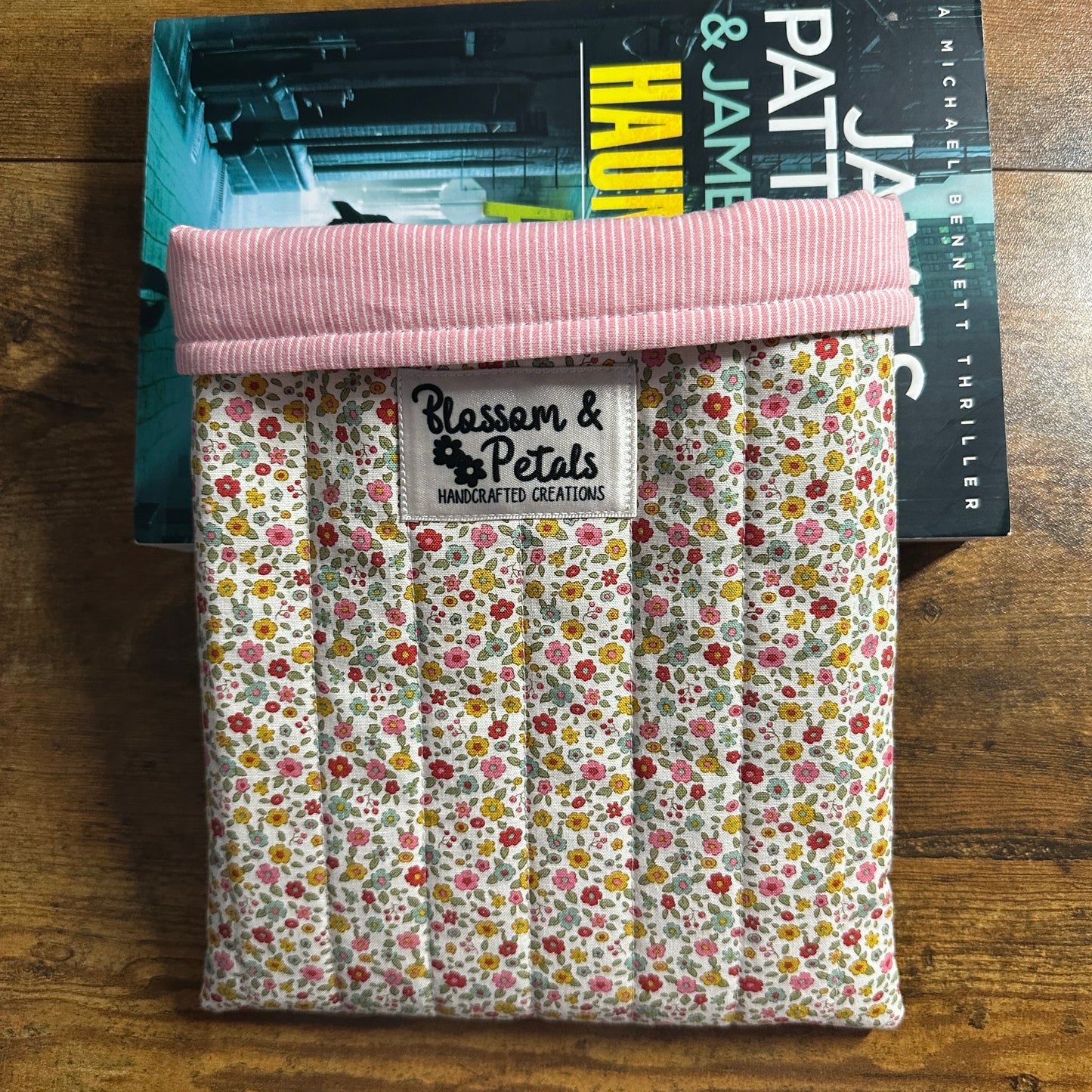 Floral fabric pouch with pink top on a book